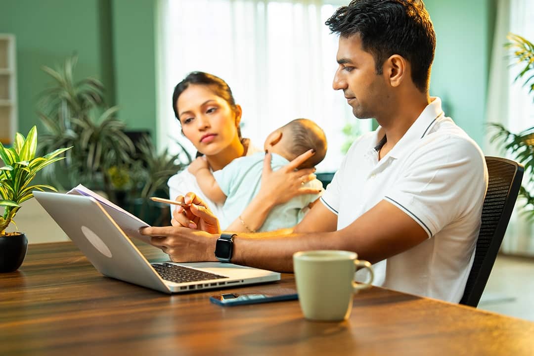 Parents with their infant child viewing and managing household expenses.